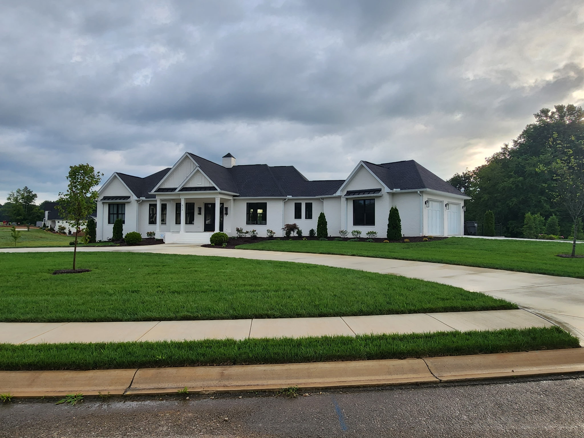 Completed white custom home with black windows and landscaped lawn