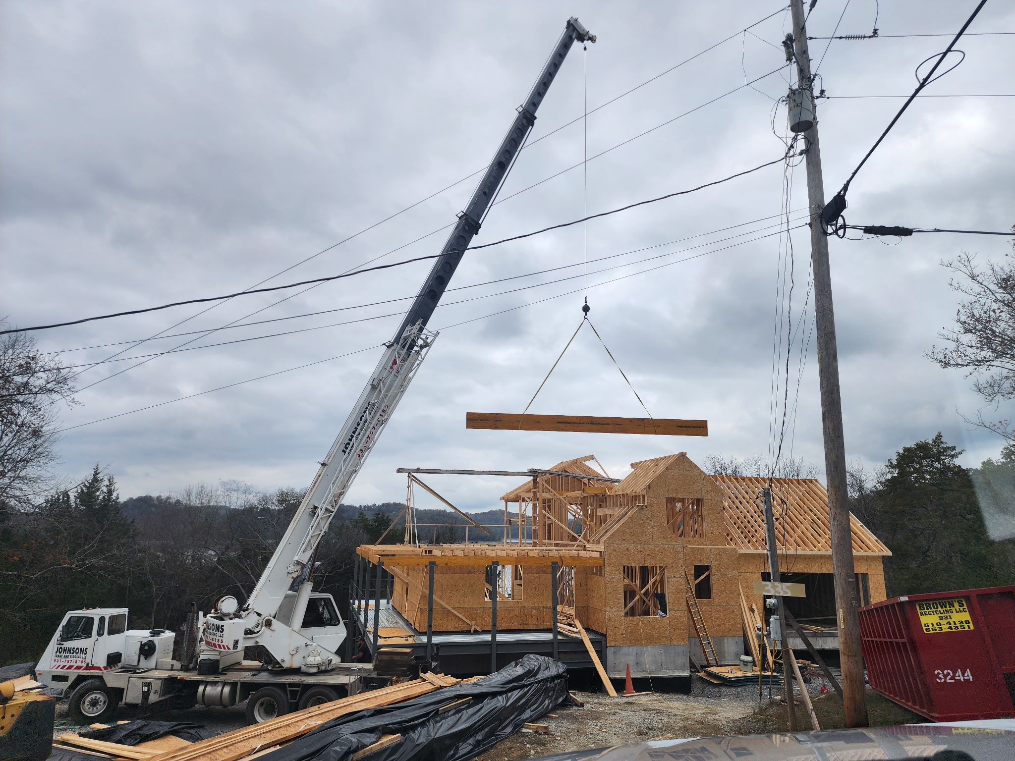 Crane setting a timber beam during custom home framing