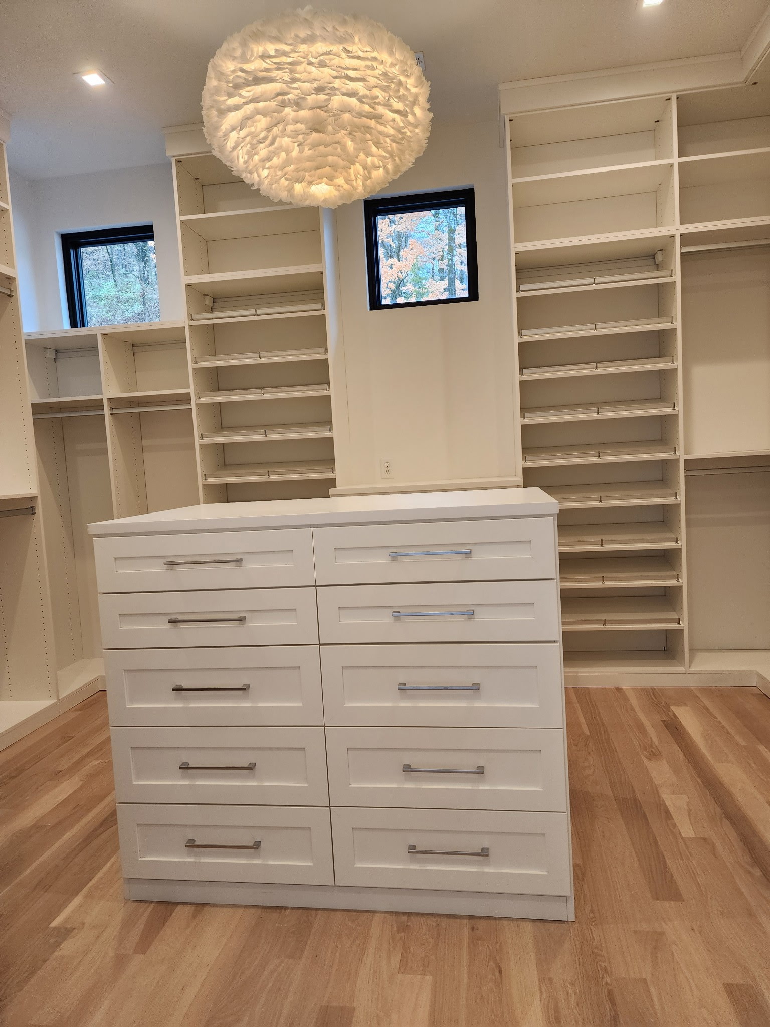 Custom walk-in closet with built-in shelving, a storage island, and chandelier