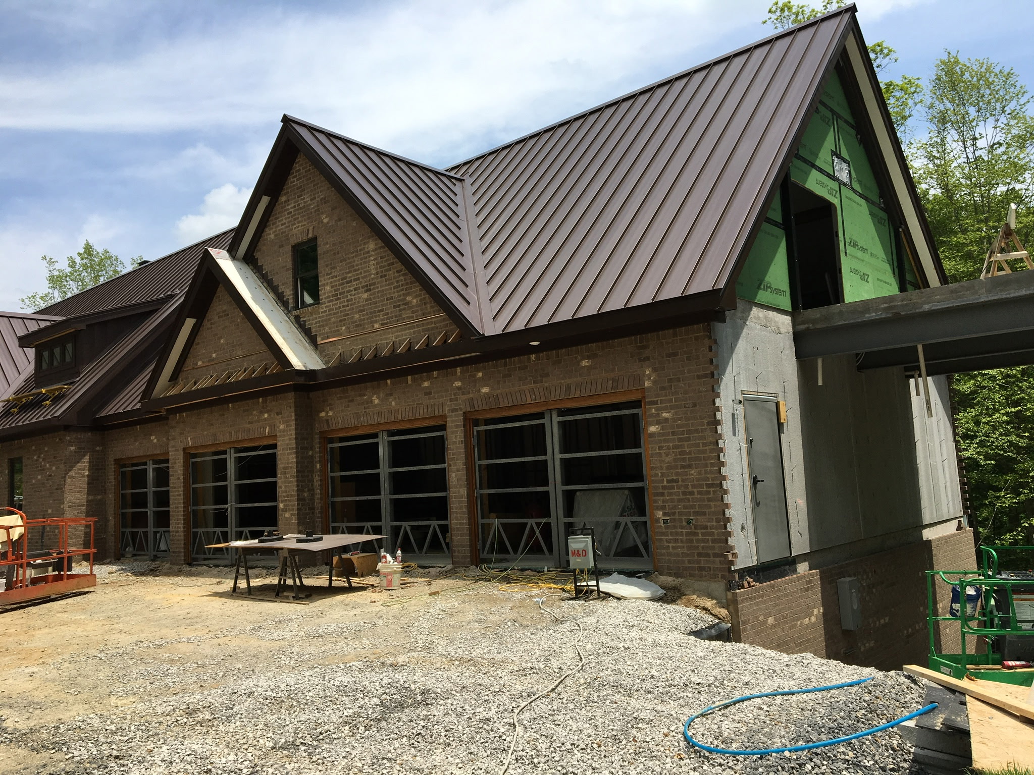 Brick custom home under construction with a standing-seam metal roof