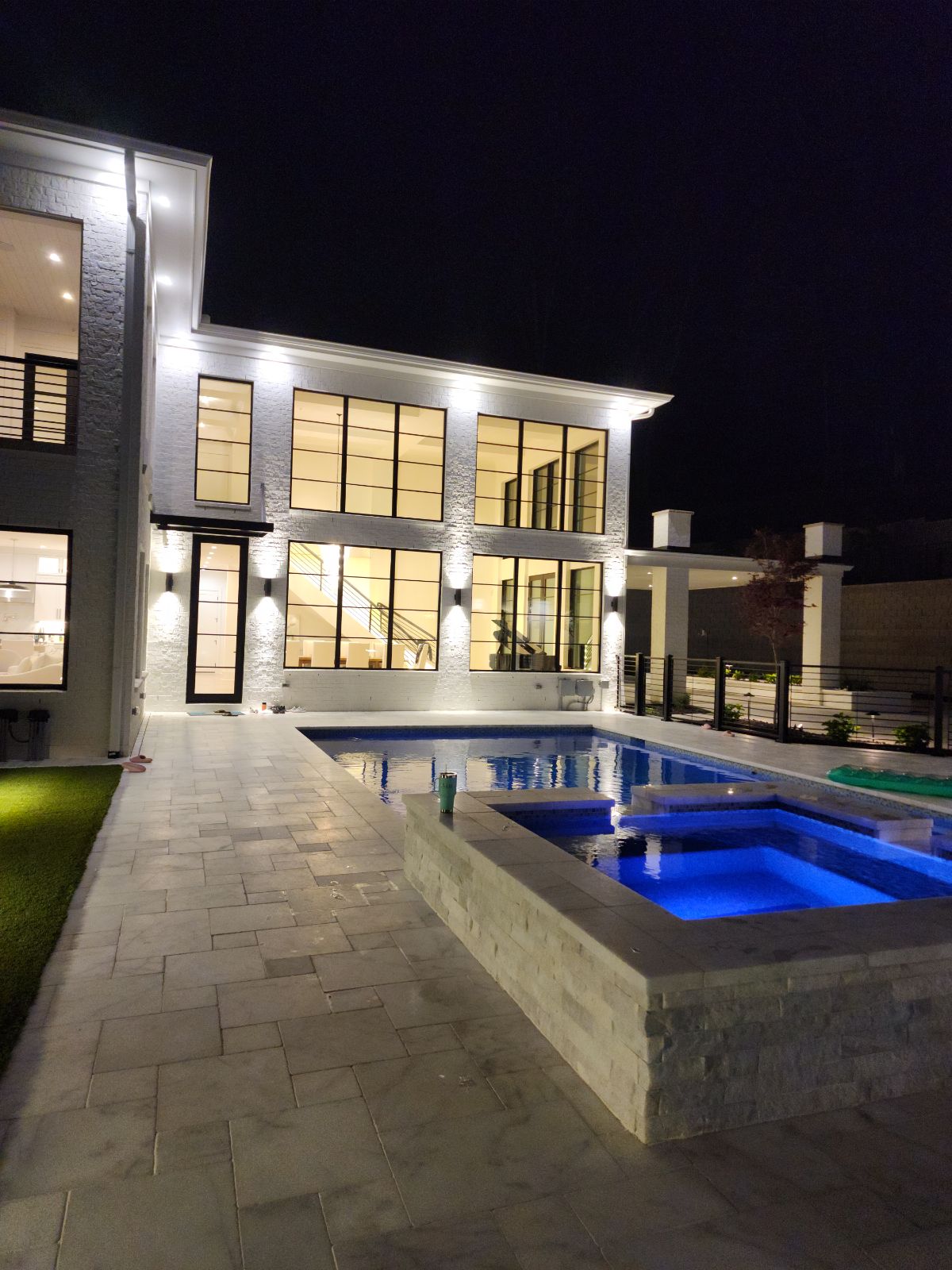 Illuminated modern custom home and swimming pool at night