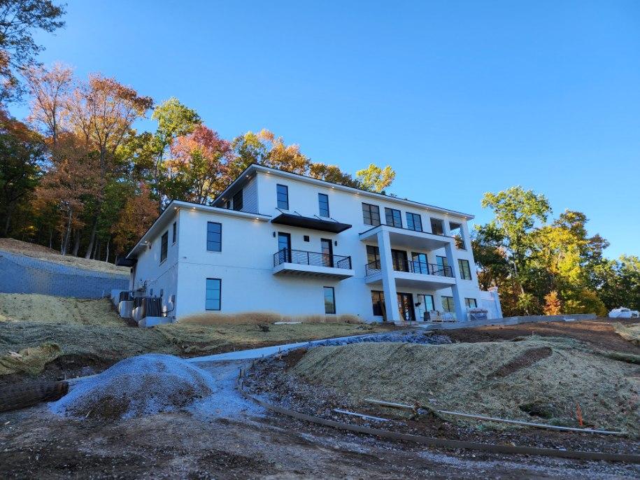 Large modern white custom home with black windows and covered balconies